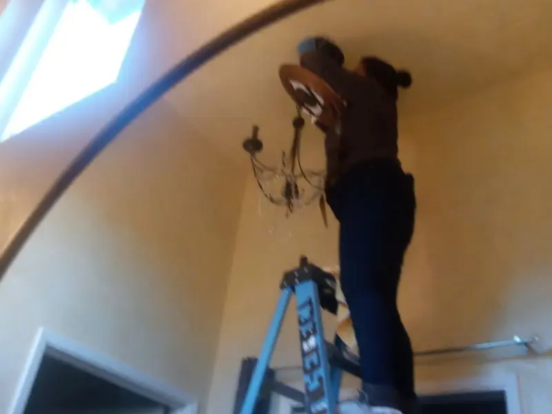 Electrician installing a chandelier in a Sartell residence
